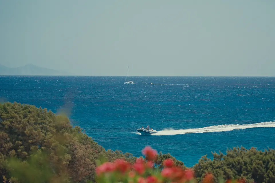 A speedboat carving across the blue sea past bougainvillea on Antiparos.